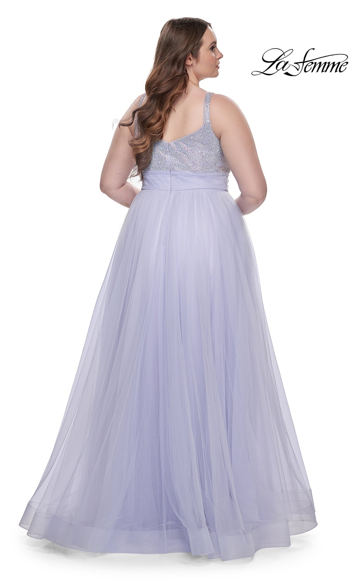 A woman wearing the La Femme Long Prom Dress 31251, featuring a beaded bodice and tulle skirt, stands facing away. The